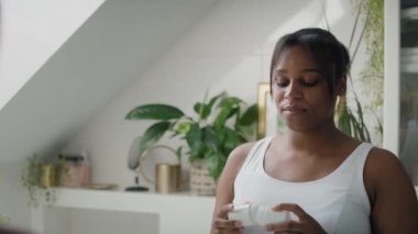Afro-Amerikalı kadın terleme önleyici krem sürdükten sonra kendini zinde hissediyor. 4K 'da kırmızı helyum kamerayla çekildi..    
