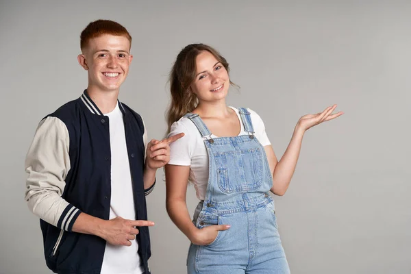 Two Teenage Students Pointing Empty Grey Wall Looking Camera —  Fotos de Stock