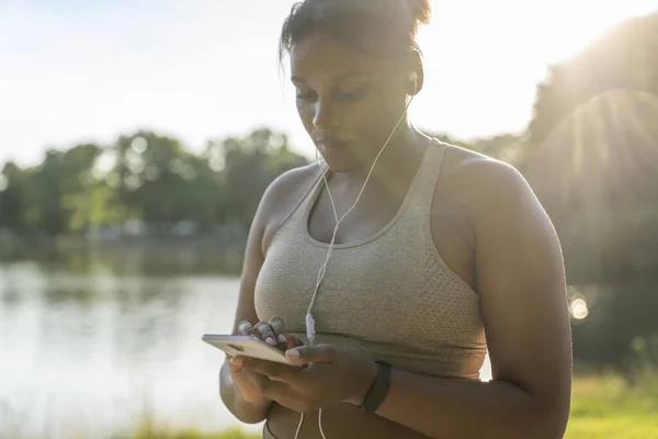 Sized African American Woman Using Mobile Phone Earphones Exercising Park — Stock fotografie