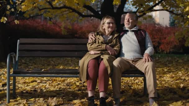 Caucasian Senior Couple Sitting Bench Park Embracing Shot Red Helium — Stockvideo