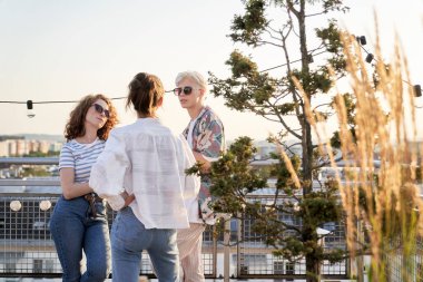 Group of caucasian young people talking at rooftop party 