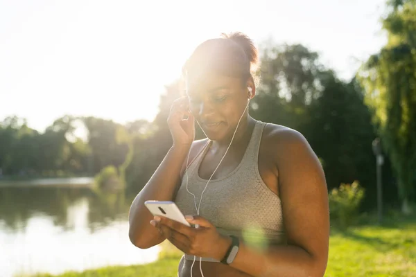 Plusz Méretű Afro Amerikai Mobiltelefonnal Fülhallgatóval Edzés Előtt Parkban Egy — Stock Fotó