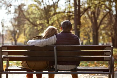 Senior caucasian couple sitting at the bench in park 