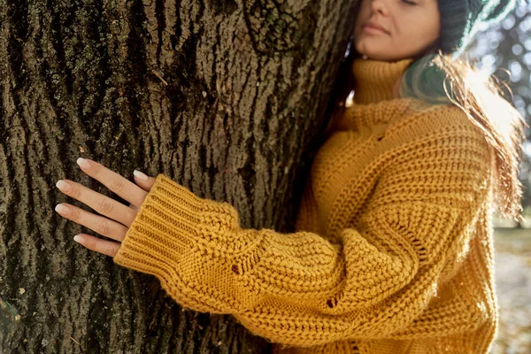 Caucasian woman holding arms around tree in park during the autumn