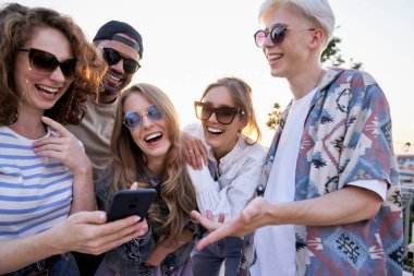 Çatıdaki partide cep telefonuna bakan bir grup etnik kökenli arkadaş 