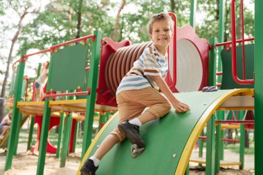 Smiling boy playing at the playground in summer day 