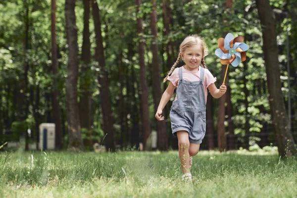 Parkta Yel Değirmeniyle Koşan Tatlı Küçük Kız — Stok fotoğraf
