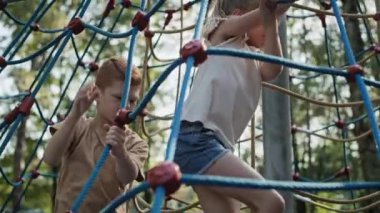 Two caucasian kids climbing at playground together. Shot with RED helium camera in 8K.    