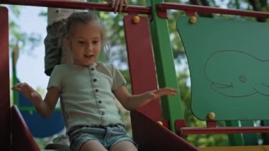 Caucasian girl playing at sliding in summer day. Shot with RED helium camera in 8K.   