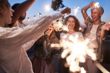 Group of friends celebrating together at the rooftop with sparkles 