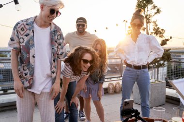 Çatıdaki partide cep telefonuna bakan bir grup etnik kökenli arkadaş 