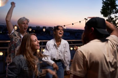 Group of happy friends dancing at the party in top of the roof                               