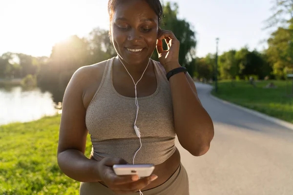 African American Woman Using Mobile Phone Earphones Exercising Park Summer — Stock fotografie