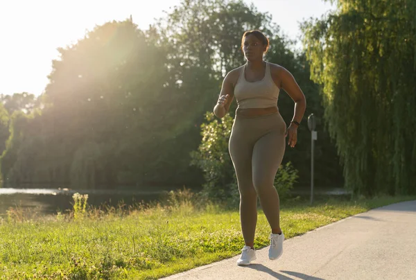 Plus size African American woman running at the park