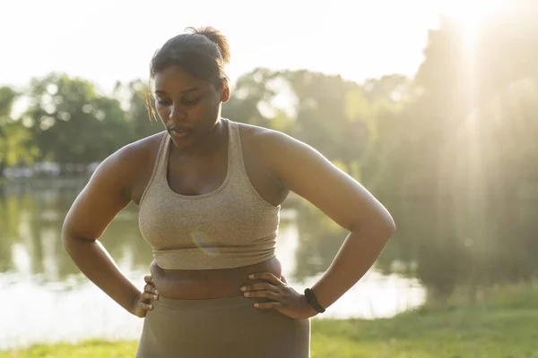 Young African American woman breathing after hard workout at the park