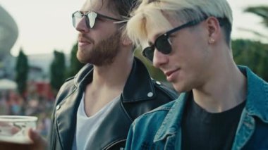 İki beyaz erkek bira içerken müzik festivalinde eğleniyorlar. 8K 'da kırmızı helyum kamerayla çekildi.. 