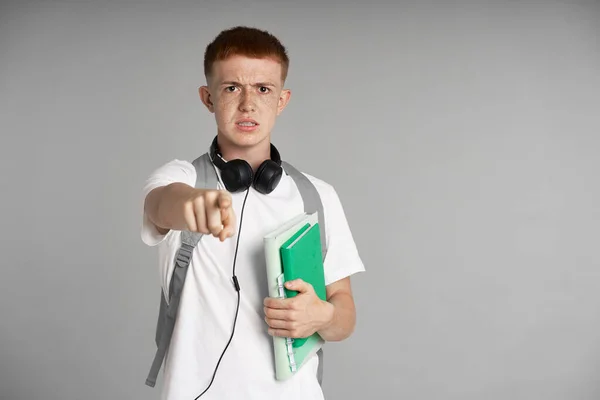 Frustrated Redhead Teenage Boy Backpack Holding Books Pointing Finger Camera — Stockfoto