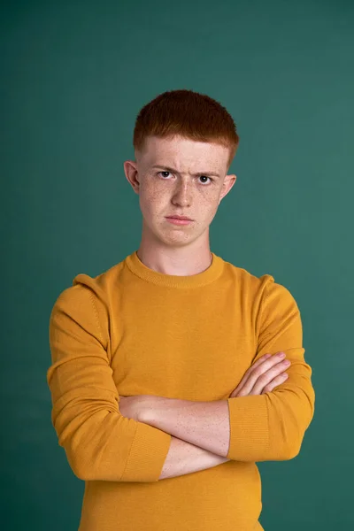 Portrait of teenage boy of ginger hair with dissatisfied face expression
