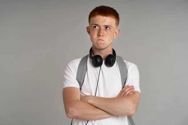 Caucasian teenage boy of ginger hair with dissatisfied face expression looking up