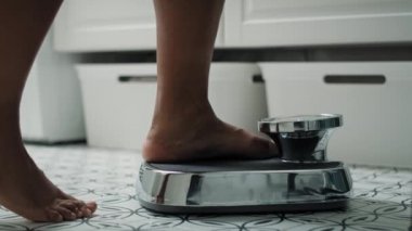 Feet of unrecognizable African-American woman stepping on the bathroom scale. Shot with RED helium camera in 8K. 