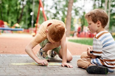 Group of boys coloring with chalk in summer day
