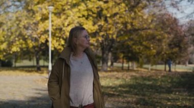 Caucasian senior woman walking alone at the park in autumn. Shot with RED helium camera in 4K 
