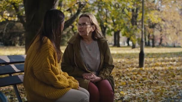 Caucasian Women Sitting Together Bench Park Autumn Shot Red Helium — Vídeo de stock