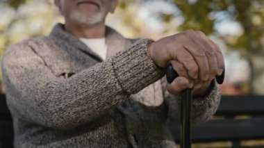 Close up serious old caucasian man sitting on bench in park. Shot with RED helium camera in 8K   