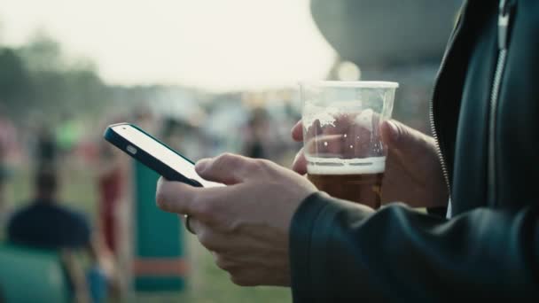 Unrecognizable Caucasian Man Browsing Phone Music Festival While Drinking Beer — Vídeo de stock