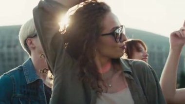 Smiling young caucasian woman with curly hair dancing at music festival among friends. Shot with RED helium camera in 8K. 
