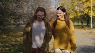 Caucasian women walking together in park in autumn. Shot with RED helium camera in 4K     