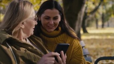 Caucasian women checking the mobile phone at park. Shot with RED helium camera in 4K     