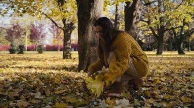 Caucasian adult woman collecting leaf in autumn. Shot with RED helium camera in 4K  