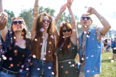 Group of young caucasian friends dancing and having fun on music festival among confetti 