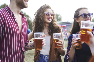 Group of friends spending time together at music festival and drinking beer