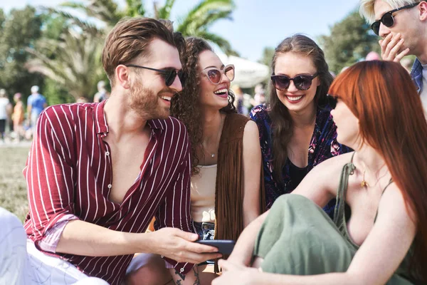 Group Friends Sitting Together Grass Music Festival Looking Mobile Phone — Foto de Stock