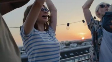 Caucasian friends dancing at the party in top of the roof. Shot with RED helium camera in 8K.  