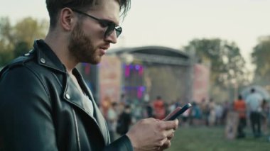 Young caucasian man on music festival using phone. Shot with RED helium camera in 8K. 