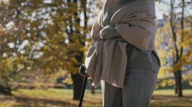 Senior woman with walking stick at the park. Shot with RED helium camera in 8K  