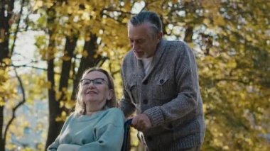 Senior man pushing woman on wheelchair in park. Shot with RED helium camera in 8K  