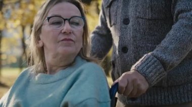 Close up of senior man pushing woman on wheelchair in park. Shot with RED helium camera in 8K