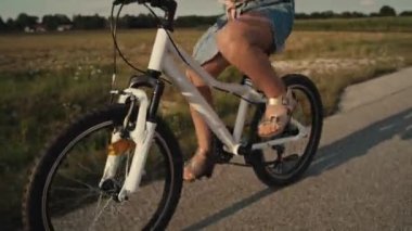 Tilt up of elementary age caucasian girl riding a bike bike at sunset time. Shot with RED helium camera in 8K.  