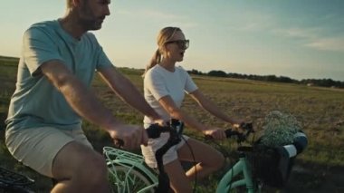 Cheerful caucasian couple of middle age riding a bike on sunset on village road. Shot with RED helium camera in 8K.   