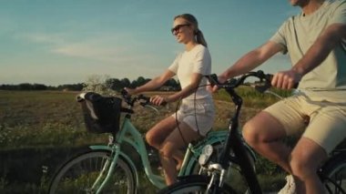 Side view of playful caucasian couple having fun while riding a bike on sunset on village road. Shot with RED helium camera in 8K.   