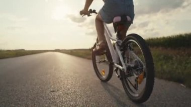 Close up of unrecognizable little caucasian girl riding a bike bike at sunset time. Shot with RED helium camera in 8K.  