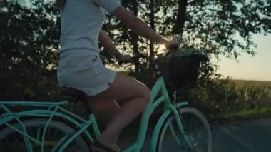 Side view of unrecognizable caucasian woman riding a bike on sunset on village road. Shot with RED helium camera in 8K.   