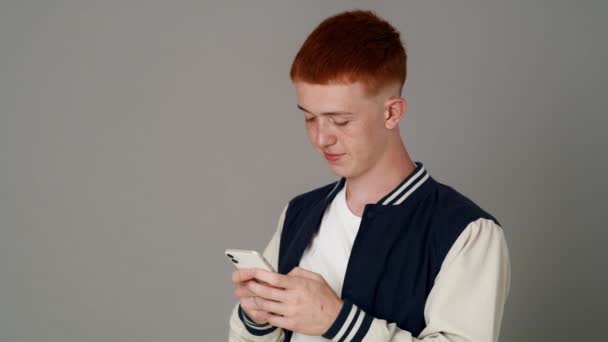 Caucasian Teenage Male Student Using Mobile Phone Grey Background Looking — Vídeos de Stock