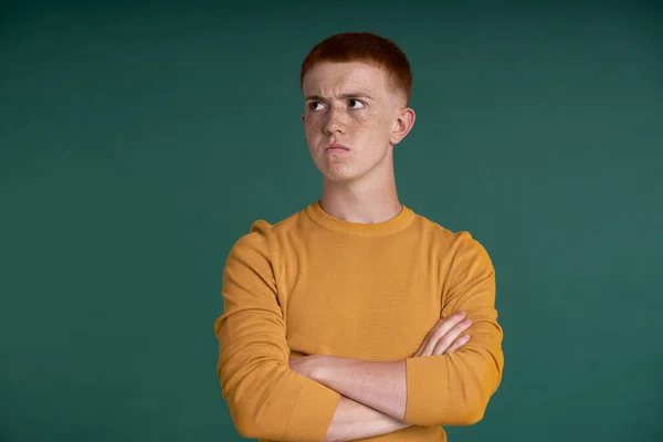 Caucasian teenage boy of ginger hair with dissatisfied face expression
