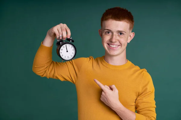 Caucasian Red Head Boy Holding Alarm Clock Pointing — Zdjęcie stockowe