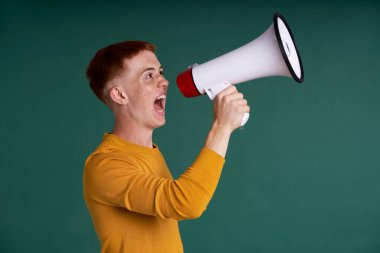 Caucasian red head teenager screaming through a megaphone